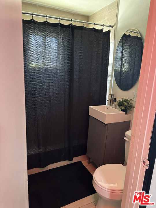 bathroom featuring curtained shower, tile patterned flooring, vanity, and toilet