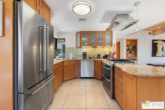 kitchen with kitchen peninsula, appliances with stainless steel finishes, light stone counters, extractor fan, and light tile patterned floors