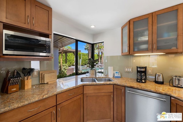 kitchen featuring tasteful backsplash, light stone counters, sink, and appliances with stainless steel finishes