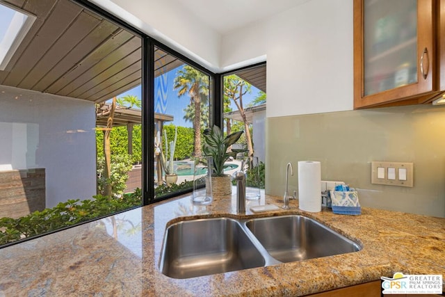 kitchen featuring light stone countertops, a healthy amount of sunlight, and sink