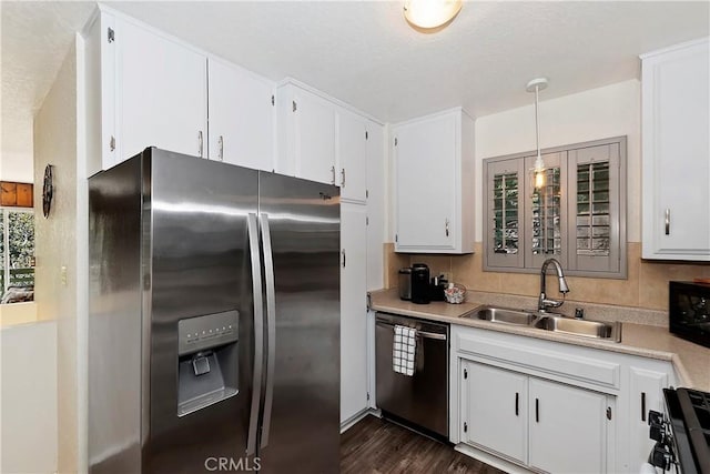 kitchen featuring decorative light fixtures, stainless steel appliances, white cabinetry, and sink