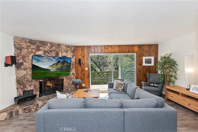 living room with a fireplace, wood-type flooring, and wood walls