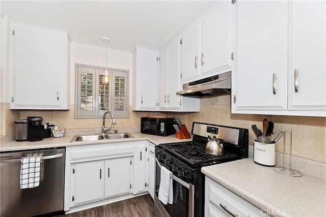 kitchen with appliances with stainless steel finishes, dark wood-type flooring, sink, pendant lighting, and white cabinets