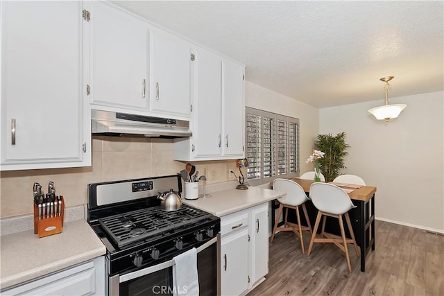 kitchen featuring light hardwood / wood-style flooring, white cabinets, decorative light fixtures, and stainless steel gas range