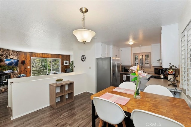 dining room featuring wood walls, sink, dark wood-type flooring, and a textured ceiling