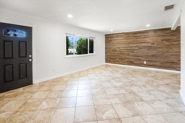 entrance foyer with ornamental molding and wooden walls