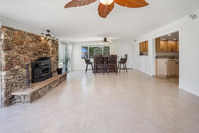 living room with ceiling fan, a textured ceiling, light tile patterned floors, and a wood stove