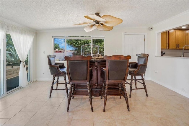 tiled dining room with a textured ceiling, ornamental molding, and ceiling fan