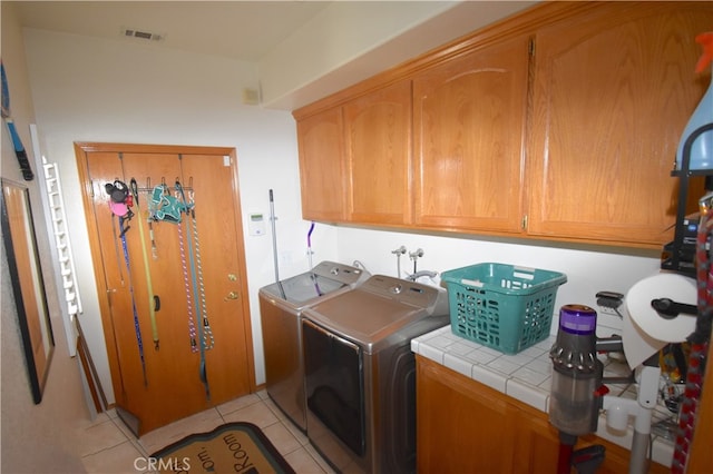 clothes washing area with cabinets, light tile patterned flooring, and separate washer and dryer