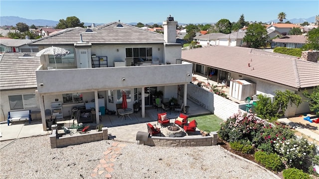 rear view of property with a patio, a mountain view, and a fire pit