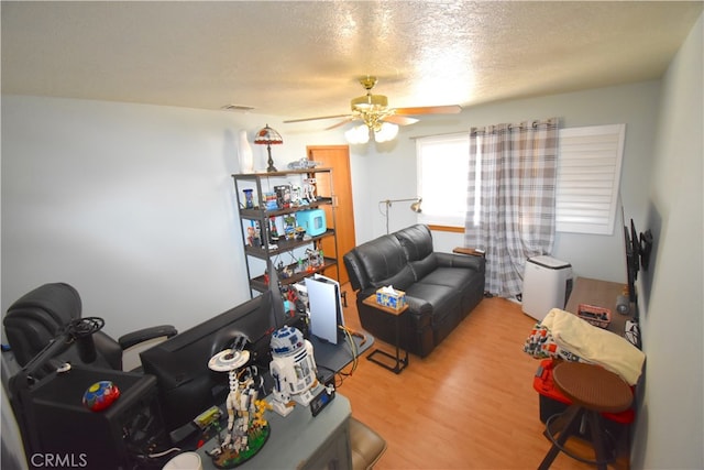 living room with ceiling fan, hardwood / wood-style flooring, and a textured ceiling