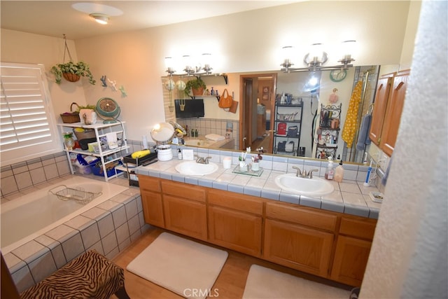 bathroom featuring tiled tub, vanity, and hardwood / wood-style floors