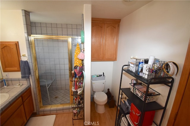 bathroom featuring walk in shower, vanity, hardwood / wood-style floors, and toilet