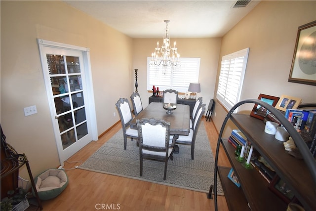 dining area featuring light wood-type flooring and an inviting chandelier