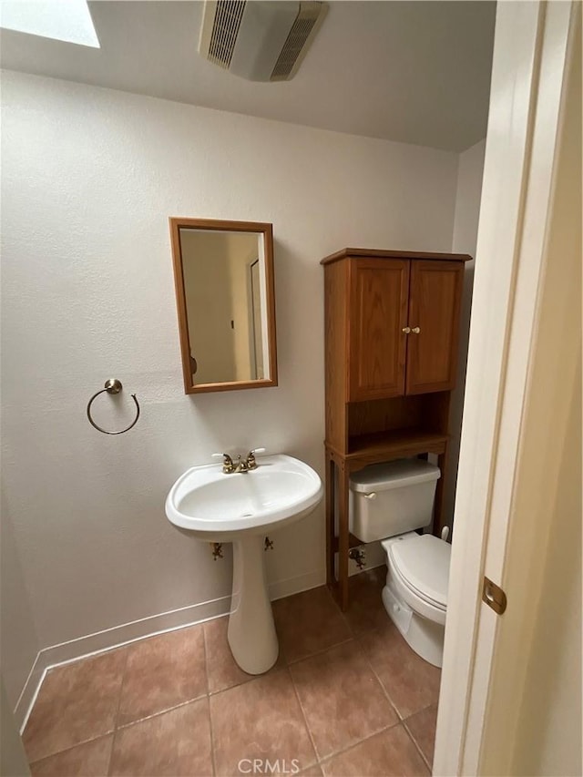 bathroom with tile patterned flooring, toilet, and a skylight