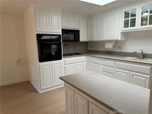 kitchen featuring white cabinetry, sink, light hardwood / wood-style flooring, and black appliances