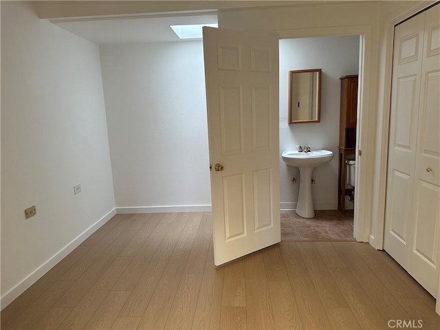 bathroom featuring wood-type flooring, sink, and a skylight