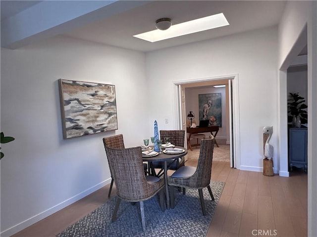 dining area with wood-type flooring and a skylight