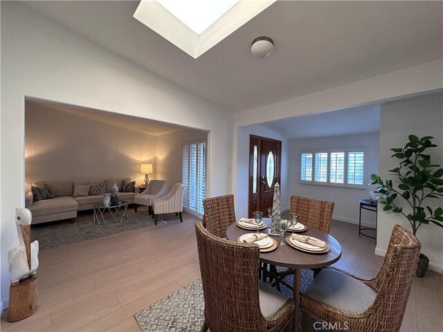 dining area featuring lofted ceiling with skylight and light wood-type flooring