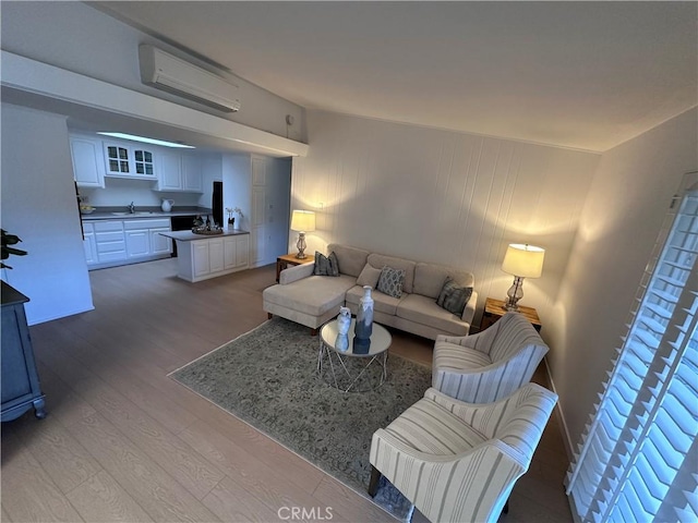 living room featuring an AC wall unit, sink, and light hardwood / wood-style flooring