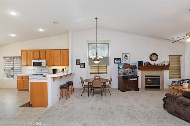 kitchen featuring hanging light fixtures, kitchen peninsula, vaulted ceiling, white appliances, and a fireplace