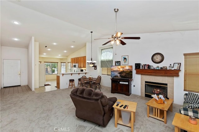 carpeted living room with a tiled fireplace, ceiling fan, a healthy amount of sunlight, and lofted ceiling