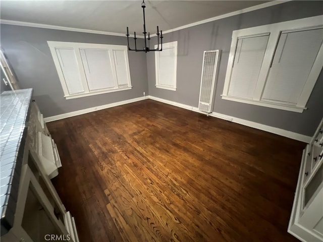 unfurnished dining area featuring dark hardwood / wood-style floors, crown molding, and an inviting chandelier