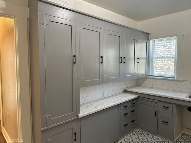 kitchen with light stone counters, decorative backsplash, light tile patterned floors, and gray cabinetry