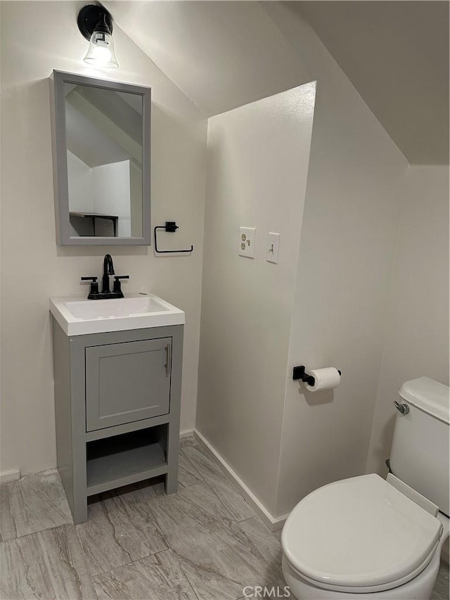 bathroom featuring toilet, vaulted ceiling, and vanity