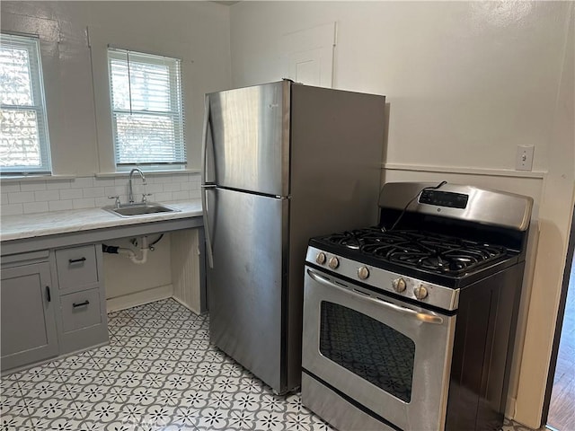 kitchen featuring sink, a wealth of natural light, tasteful backsplash, and stainless steel gas range oven