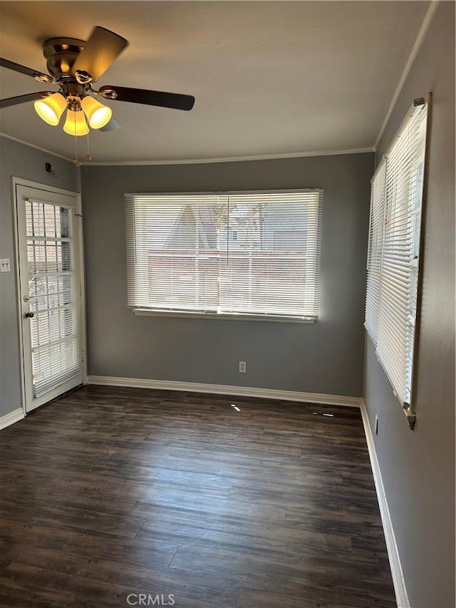 empty room with ceiling fan, a healthy amount of sunlight, ornamental molding, and dark wood-type flooring