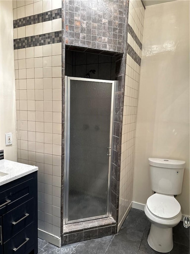 bathroom with tile patterned flooring, an enclosed shower, tile walls, toilet, and vanity