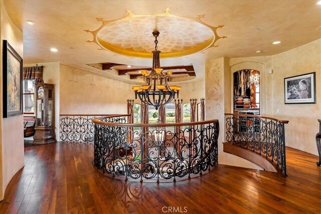 hall featuring a tray ceiling, hardwood / wood-style floors, and a notable chandelier