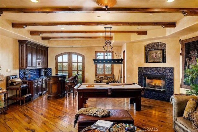 playroom featuring french doors, a fireplace, dark wood-type flooring, beamed ceiling, and pool table