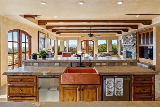 kitchen with beam ceiling, sink, a center island, french doors, and a fireplace