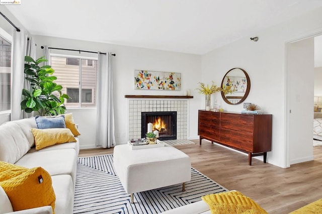 living room with light wood-type flooring and a tile fireplace