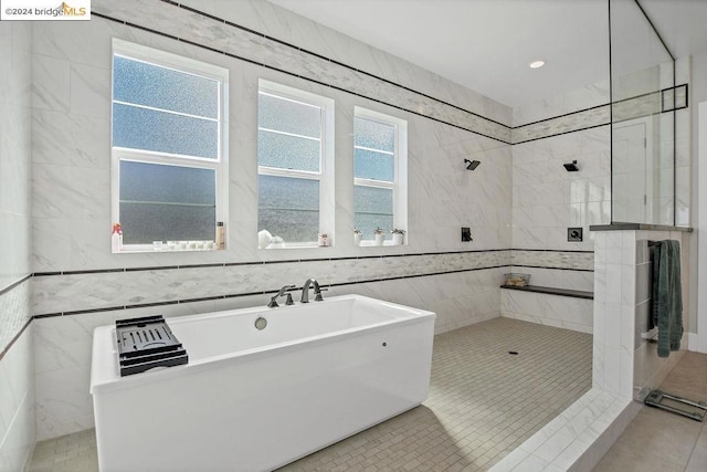 bathroom with tile patterned floors, tile walls, and plus walk in shower