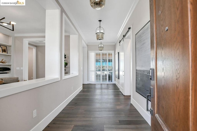 hall featuring a barn door, dark wood-type flooring, and ornamental molding