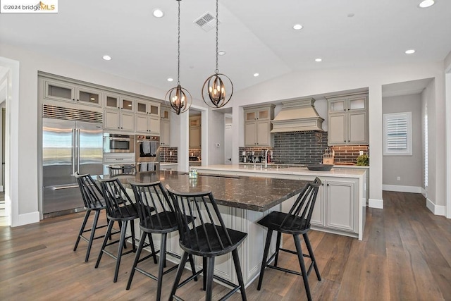 kitchen featuring a large island, stainless steel appliances, tasteful backsplash, lofted ceiling, and custom exhaust hood