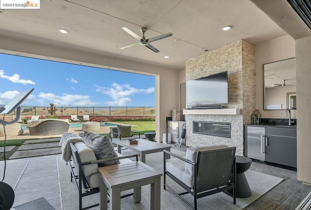 view of patio with area for grilling, a swimming pool, outdoor lounge area, ceiling fan, and sink