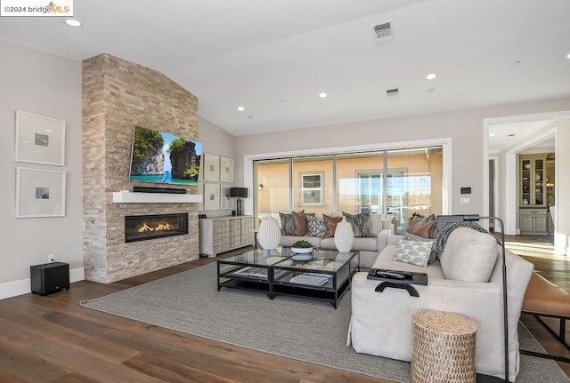 living room with a stone fireplace, dark hardwood / wood-style flooring, and lofted ceiling