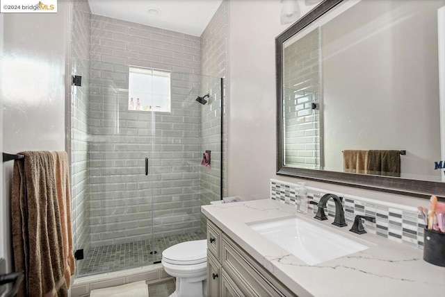 bathroom featuring tasteful backsplash, a shower with door, vanity, and toilet