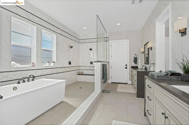 bathroom with plus walk in shower, vanity, tile patterned floors, and tile walls