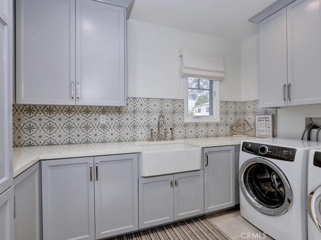 laundry room featuring washer and clothes dryer, cabinets, and sink