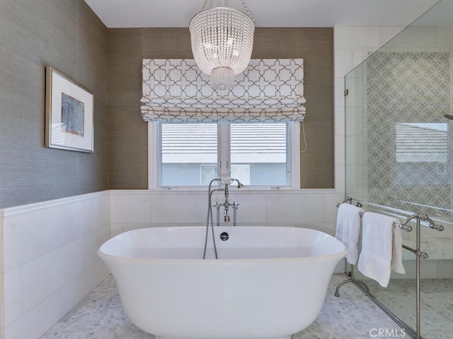 bathroom featuring shower with separate bathtub, tile walls, and a chandelier