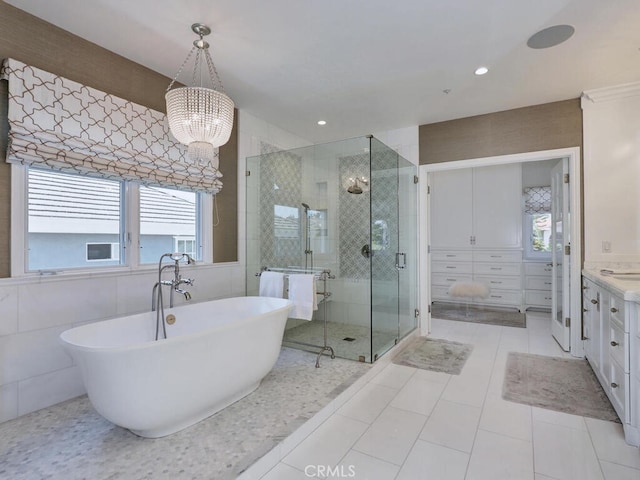 bathroom featuring tile patterned flooring, a notable chandelier, vanity, independent shower and bath, and tile walls