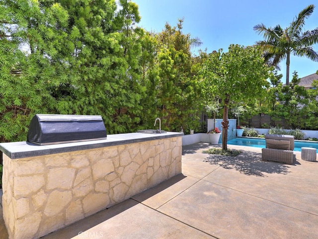 view of patio / terrace with a fenced in pool, exterior kitchen, and grilling area