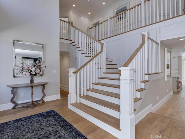 staircase featuring wood-type flooring and a high ceiling