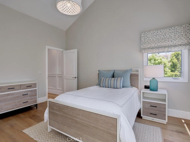 bedroom featuring light wood-type flooring and high vaulted ceiling