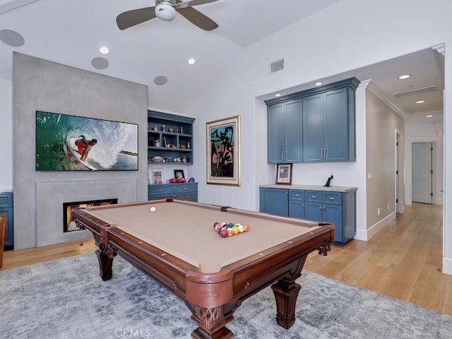 game room featuring ornamental molding, a fireplace, light hardwood / wood-style floors, and pool table